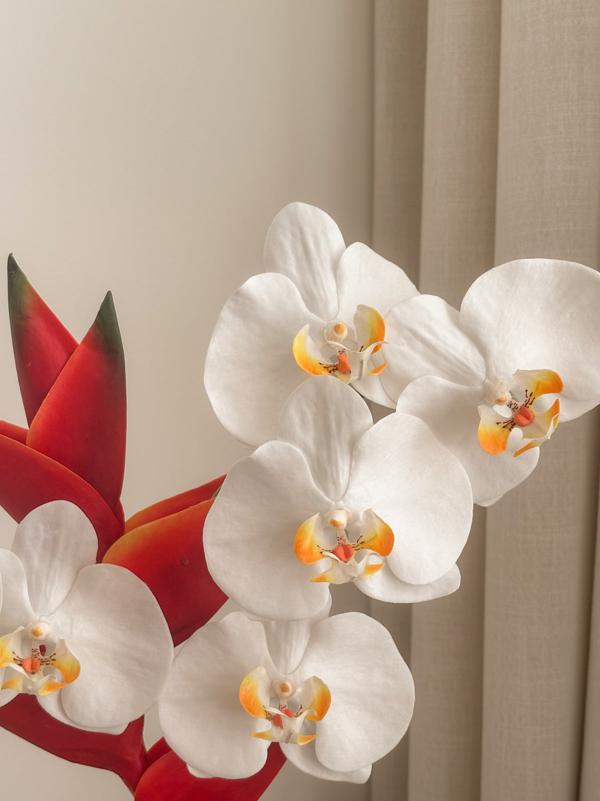 Detail view: faux white orchid and red heliconia arrangement by FAUX Dubai