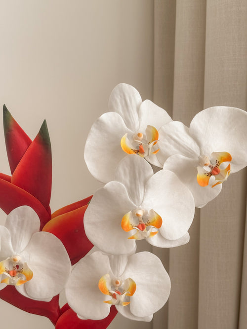 Detail view: faux white orchid and red heliconia arrangement by FAUX Dubai